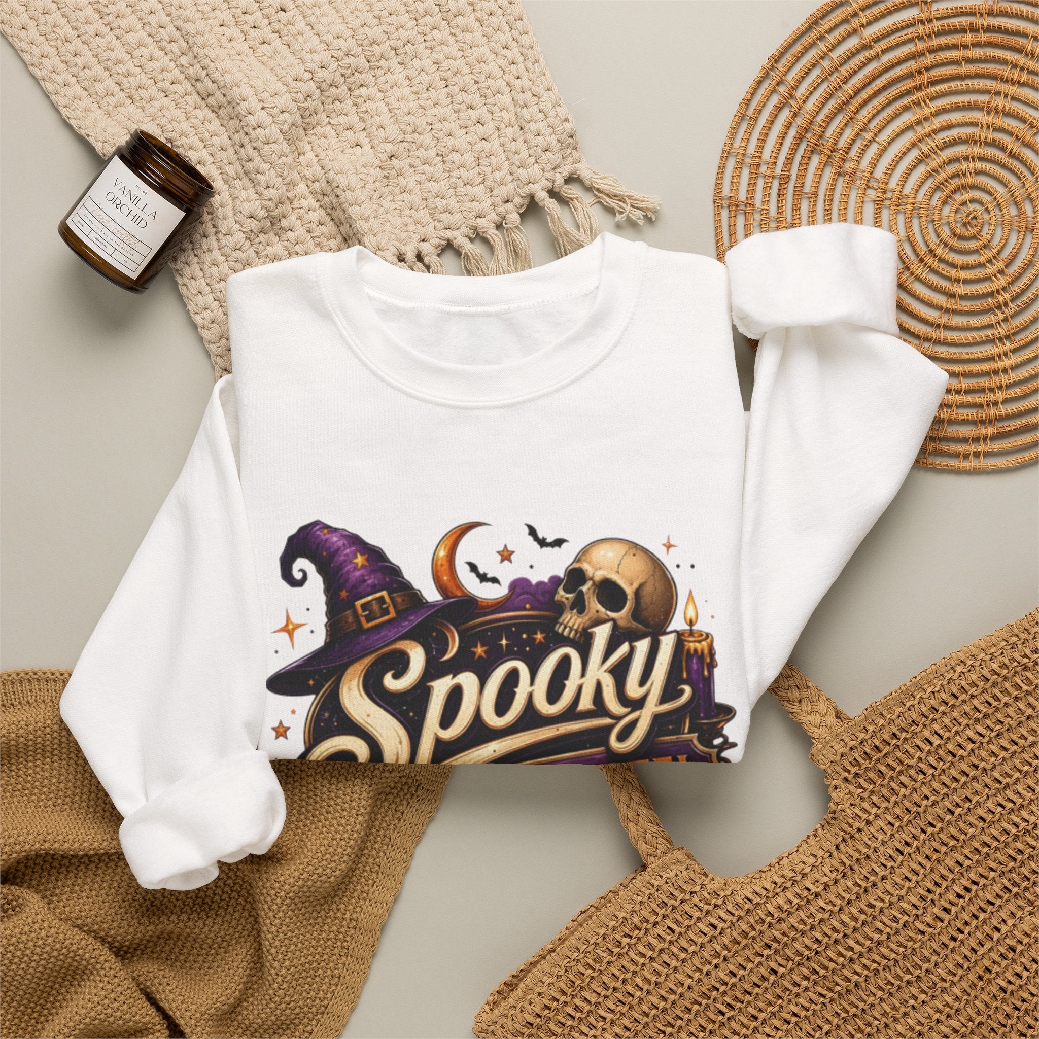White crewneck sweatshirt styled flat with a candle — neon Spooky Witch Motel sign