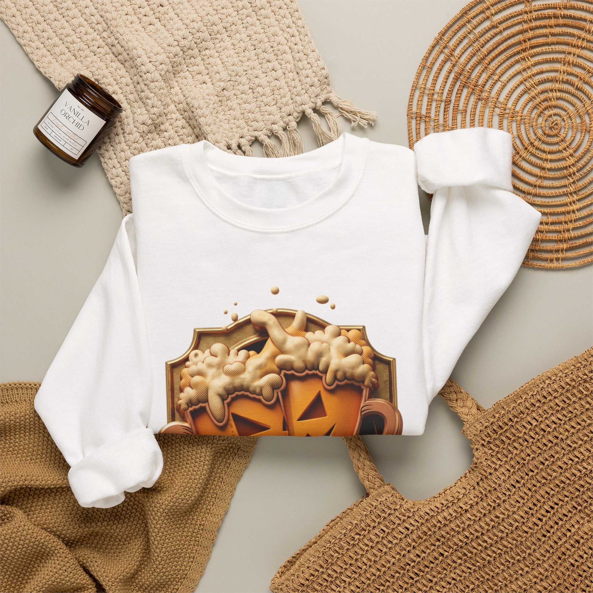 White crewneck sweatshirt styled flat with a candle — beer mugs carved as jack-o-lanterns