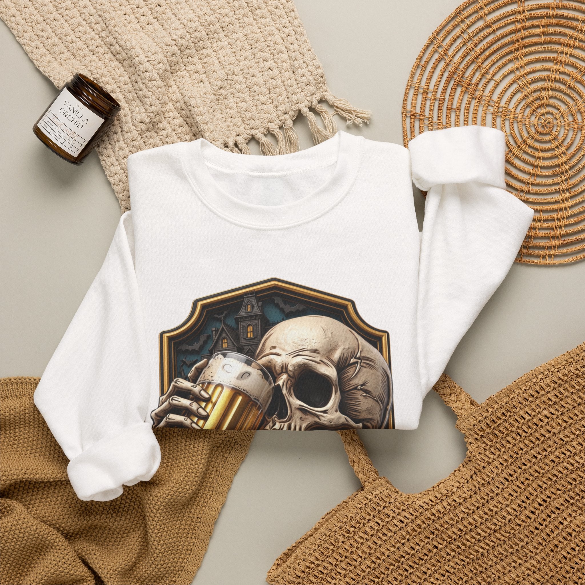 White crewneck sweatshirt styled flat with a candle — cracked skull with a beer mug