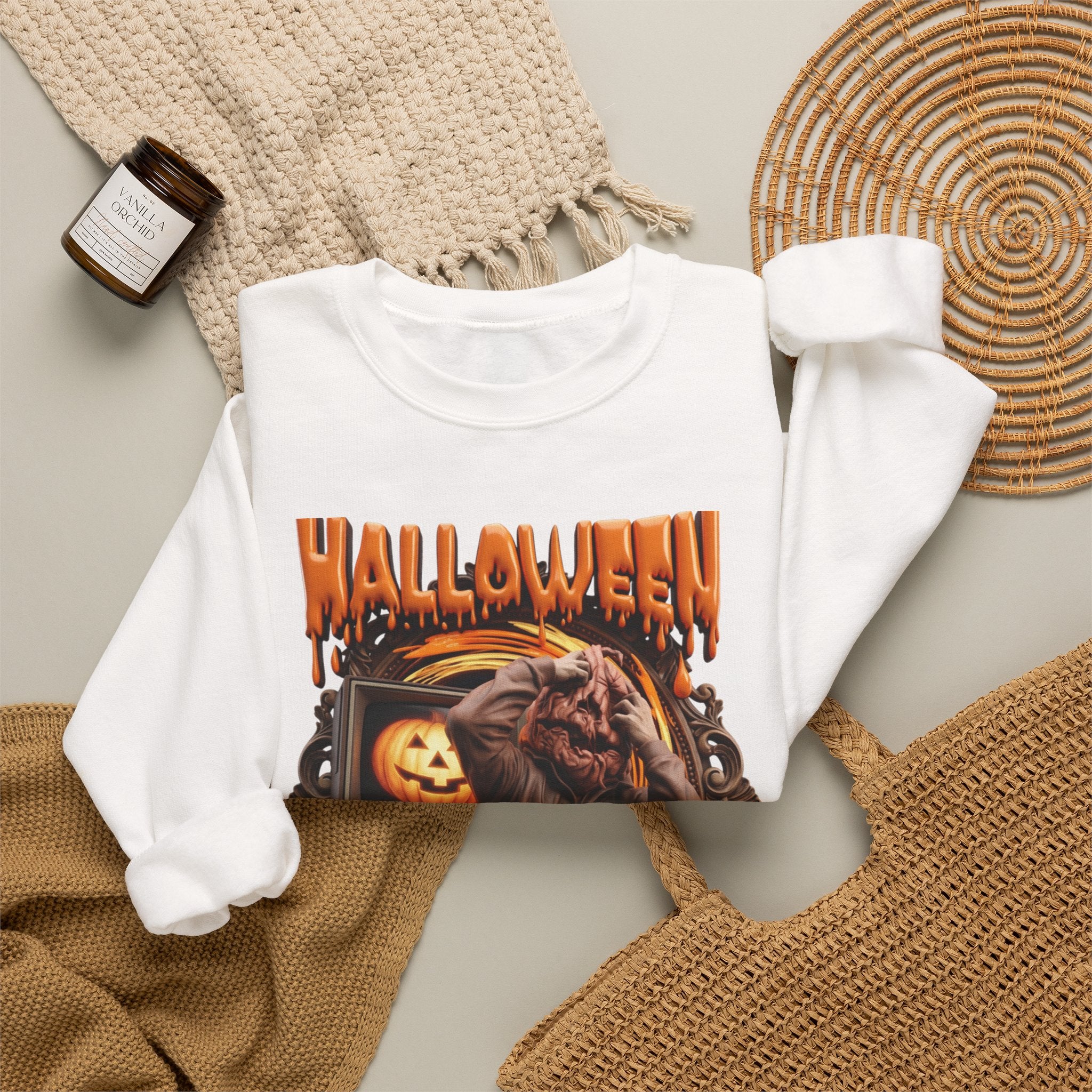 White crewneck sweatshirt styled flat with a candle — hunched monster clawing its own head