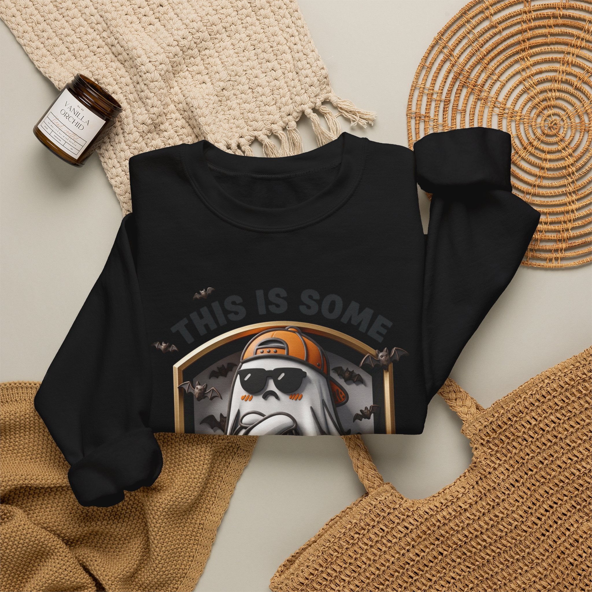 Black crewneck sweatshirt styled flat with a candle — sheet ghost in an orange cap