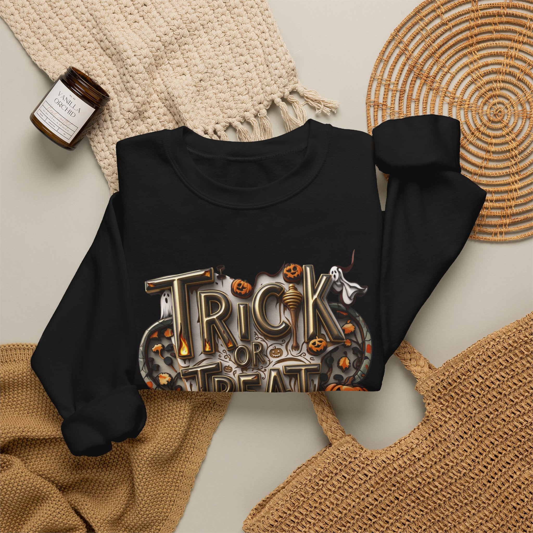 Black crewneck sweatshirt styled flat with a candle — carved Trick or Treat Yourself lettering