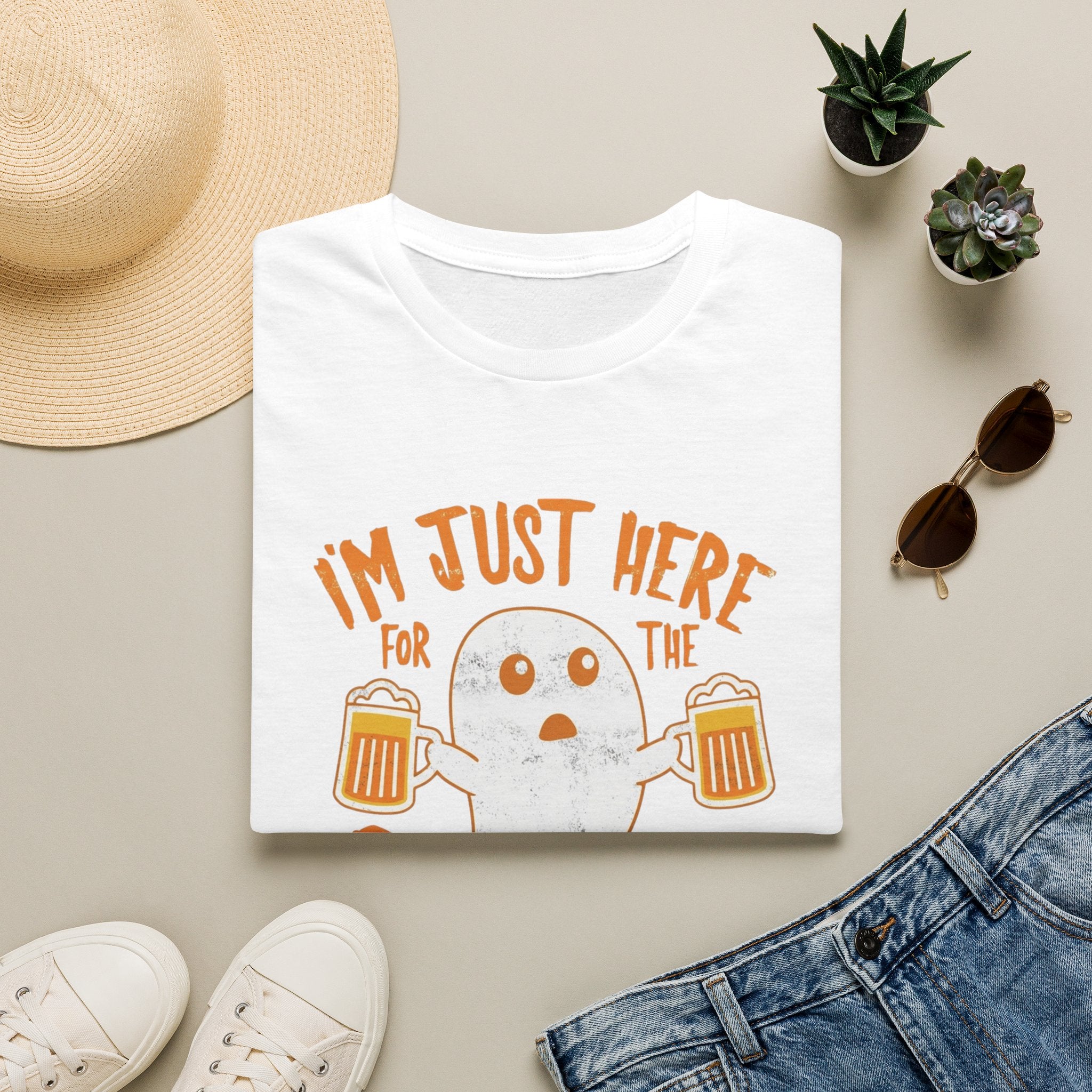 White t-shirt styled flat with a candle — wide-eyed ghost raising a frothy pint