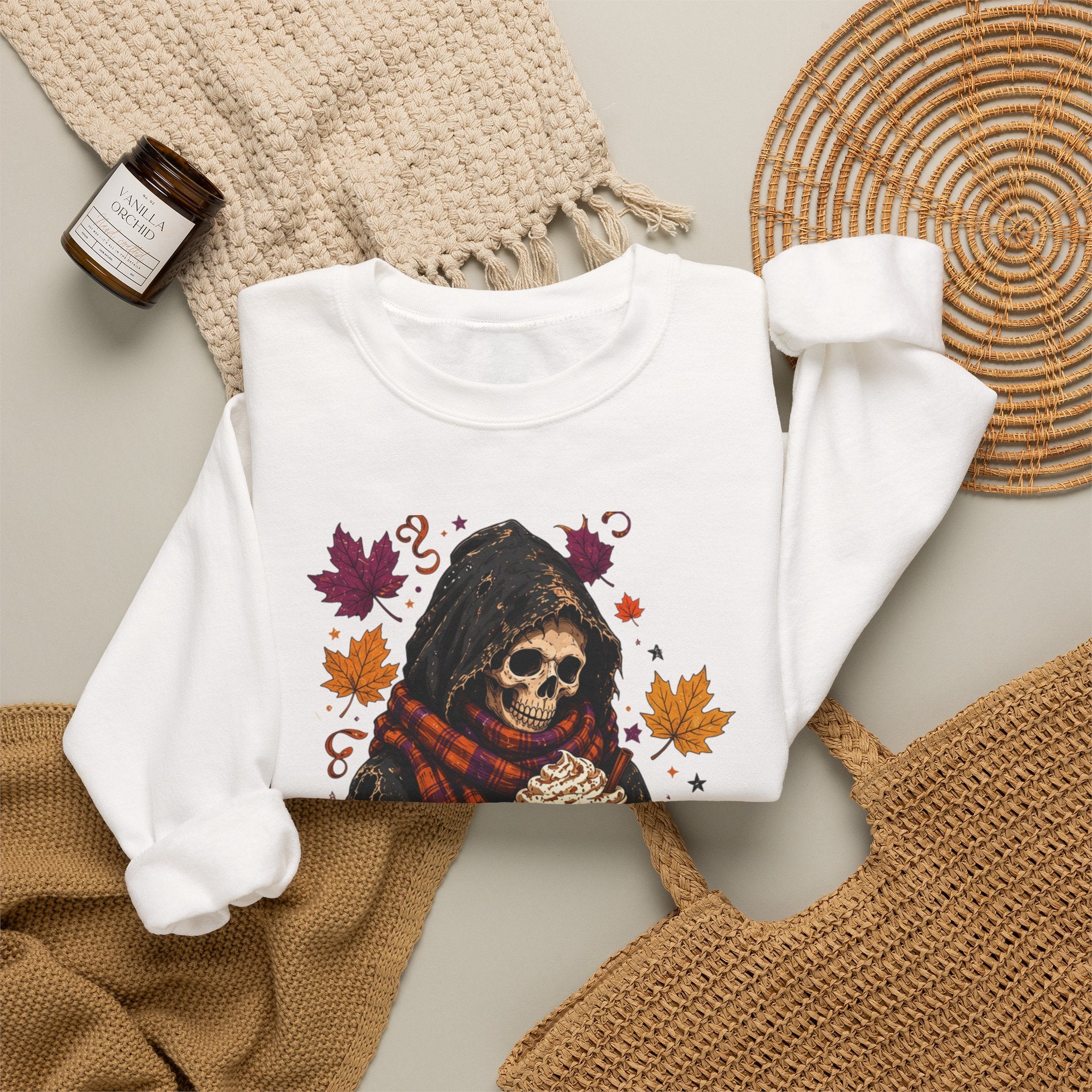 White crewneck sweatshirt styled flat with a candle — hooded skeleton with pumpkin spice drink