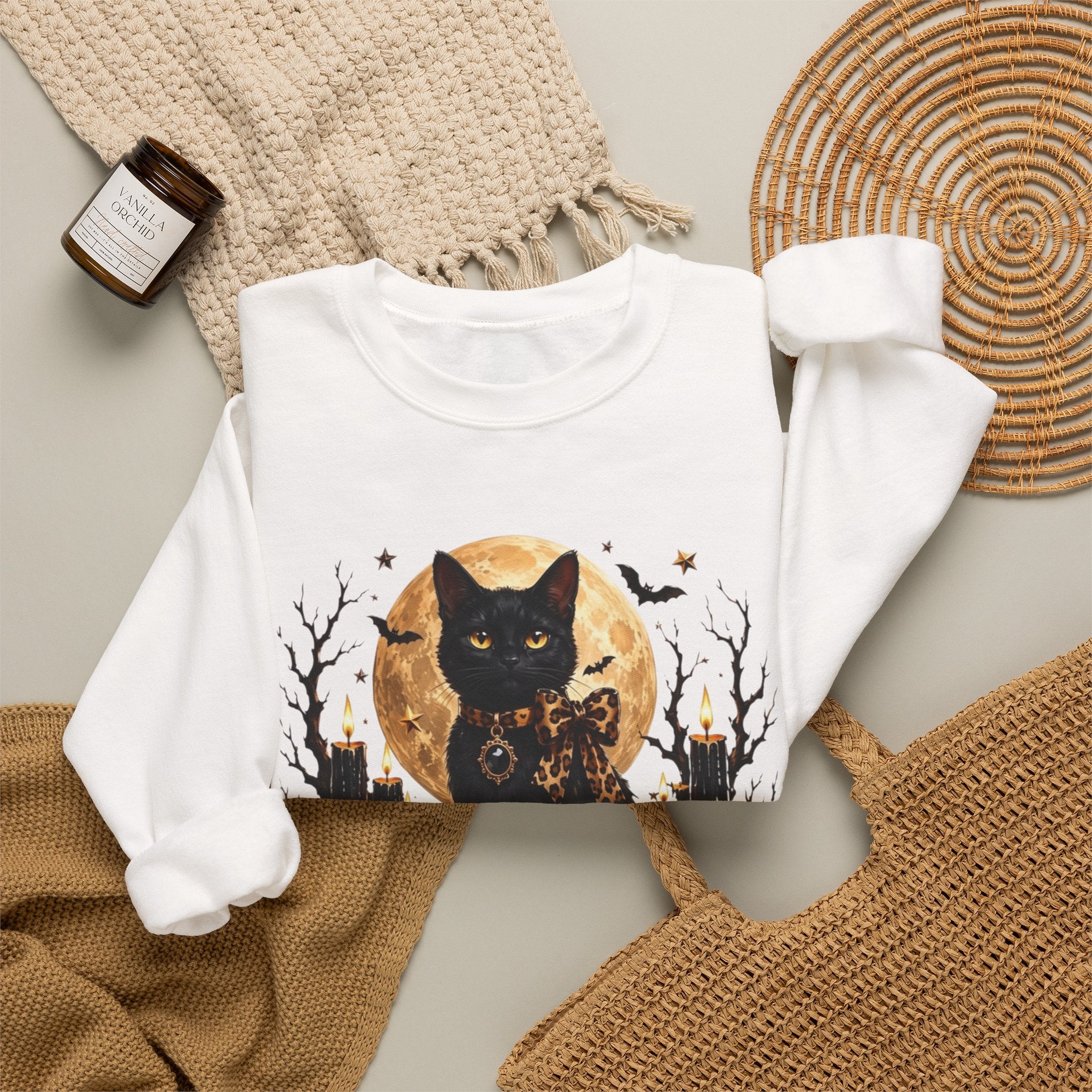 White crewneck sweatshirt styled flat with a candle — black cat before a full moon