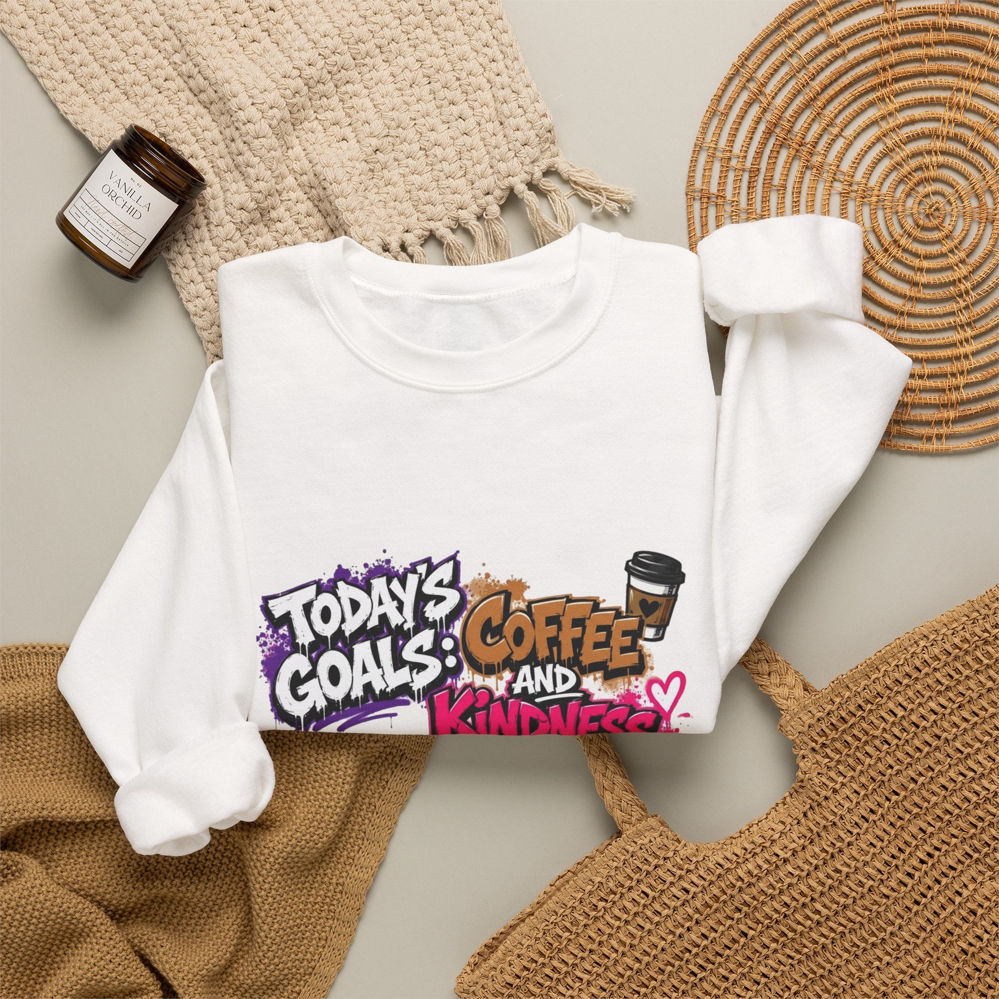 White crewneck sweatshirt styled flat with a candle — graffiti lettering in electric pinks