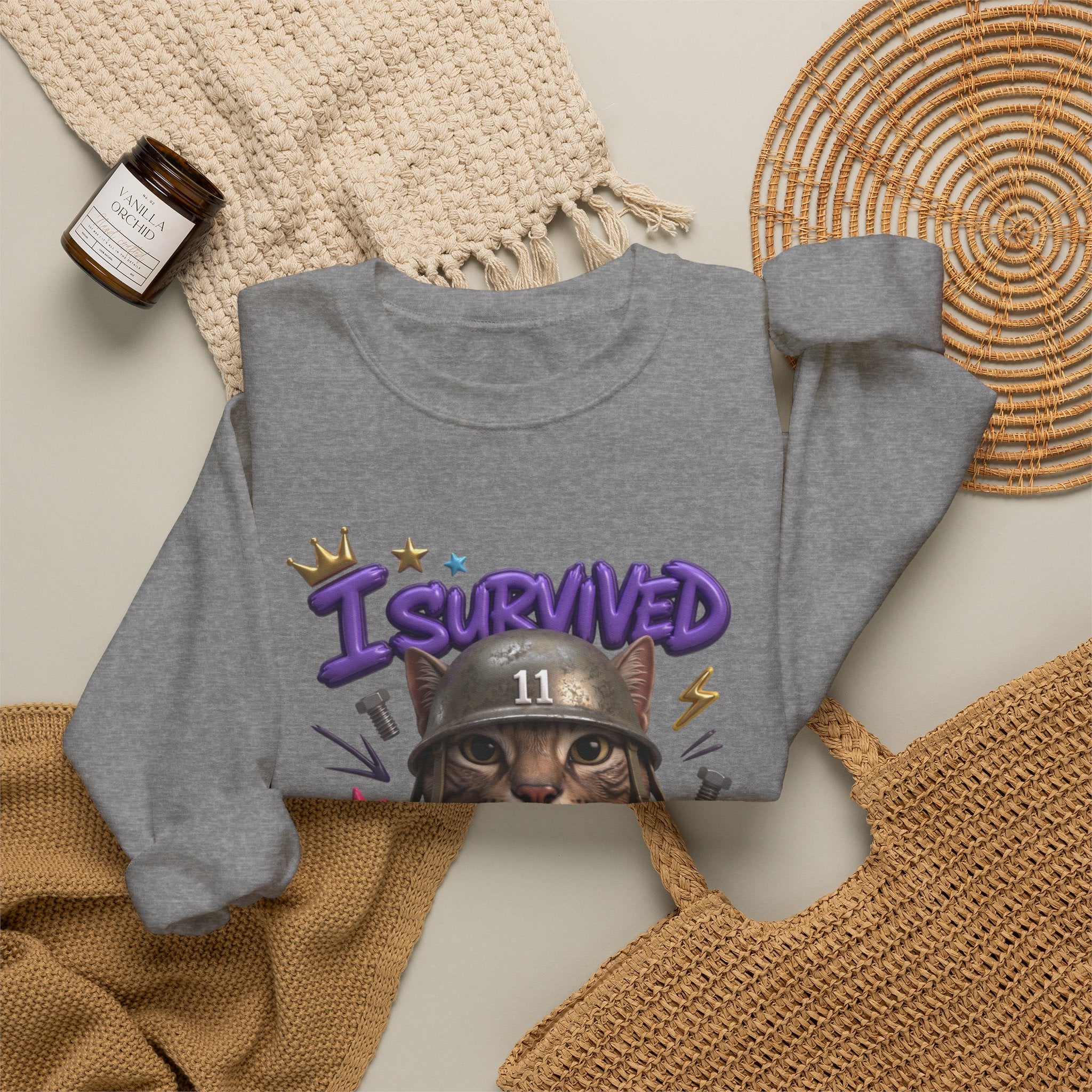 Graphite Heather crewneck sweatshirt styled flat with a candle — flat-eyed cat in a steel helmet