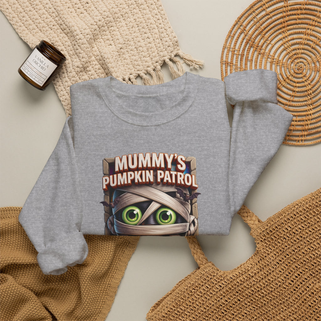 Sport Grey crewneck sweatshirt styled flat with a candle — cartoon mummy hugging a carved pumpkin