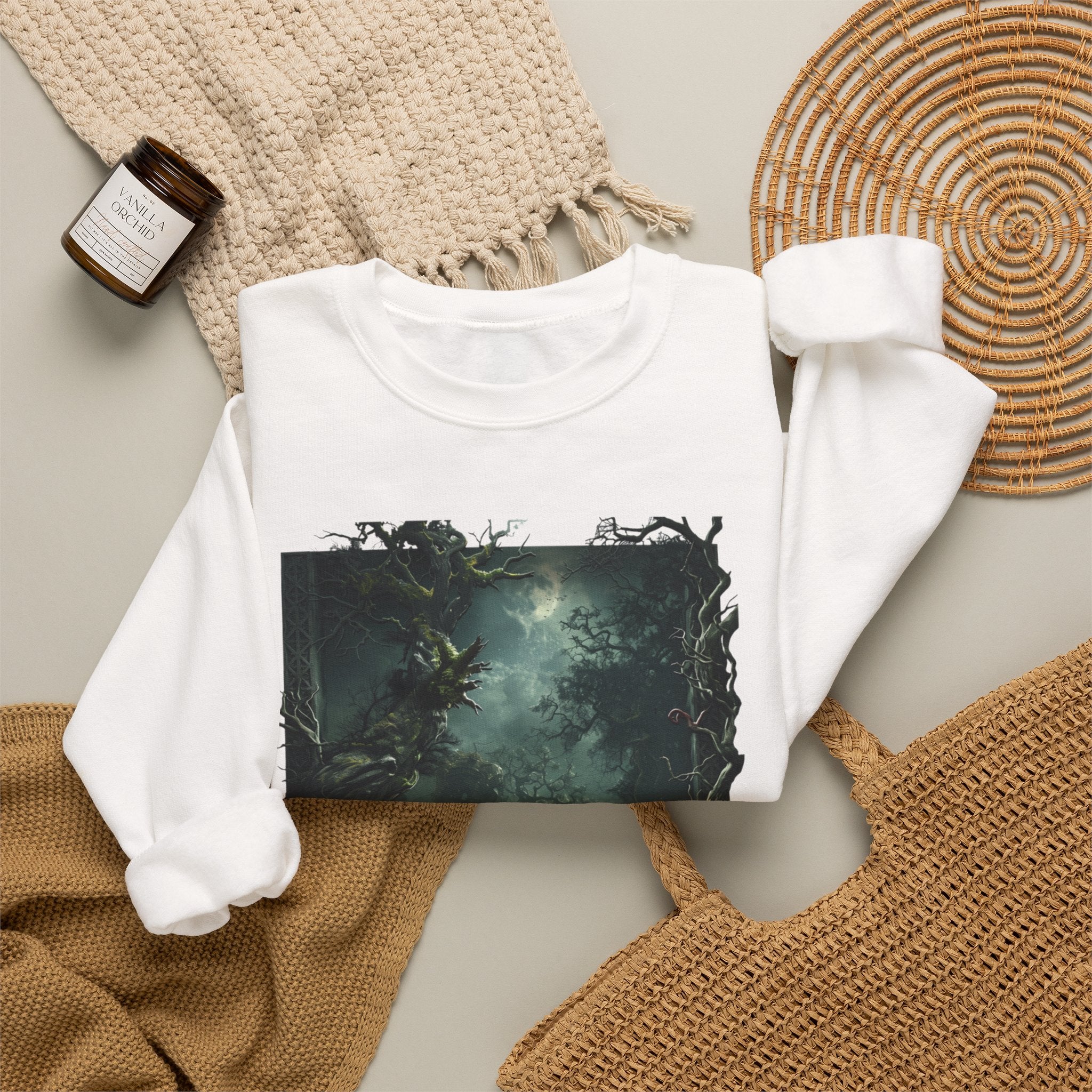 White crewneck sweatshirt styled flat with a candle — moonlit forest of gnarled mossy trees