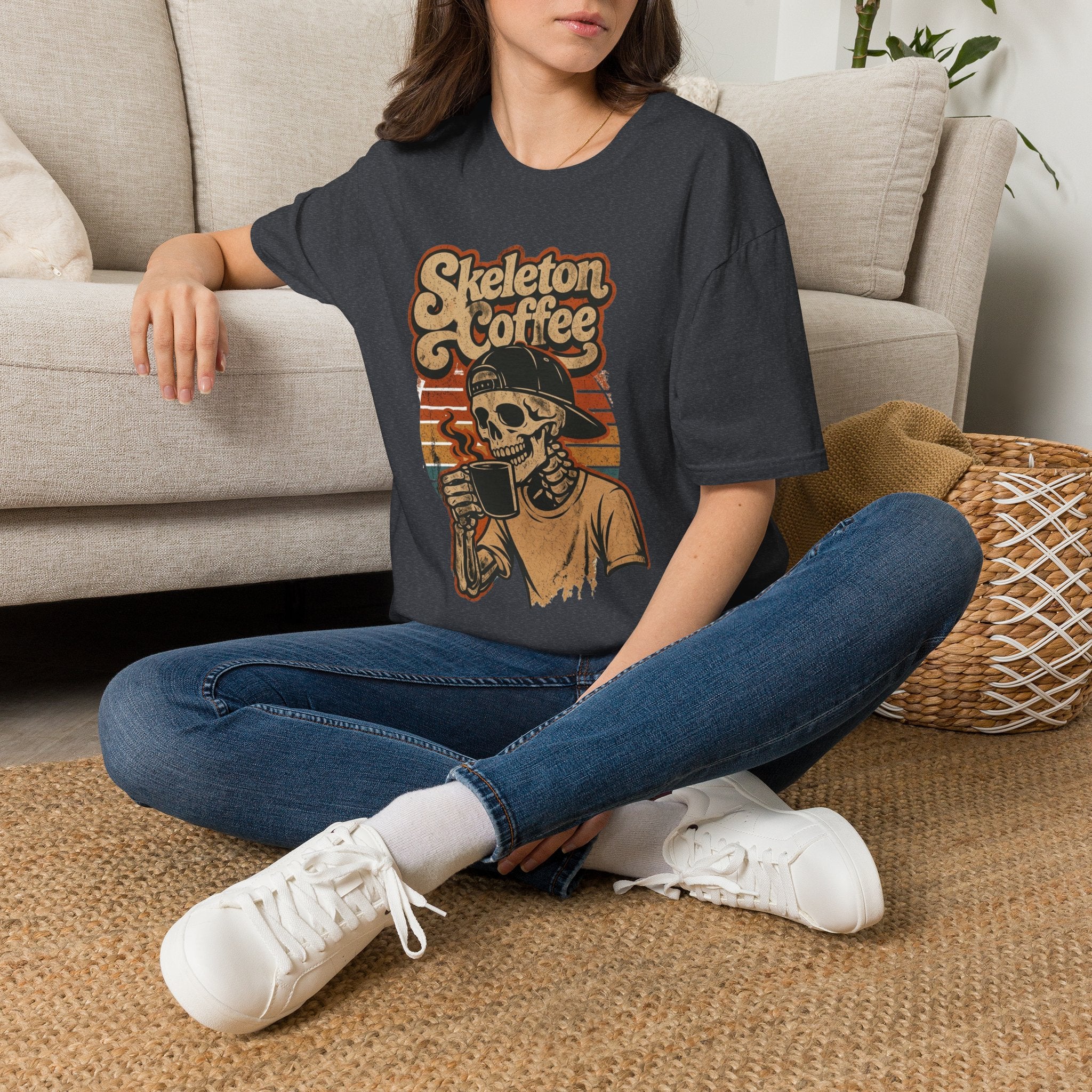 Dark Heather Grey t-shirt laid flat, printed with a skeleton in a knitted sweater raising a paper cup