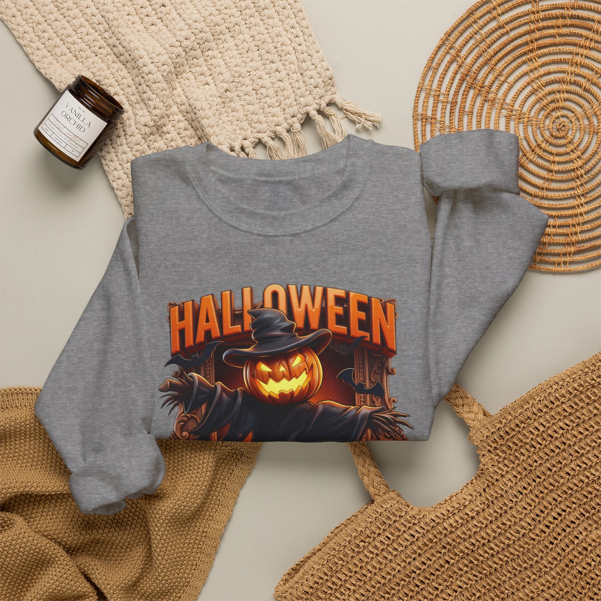 Graphite Heather crewneck sweatshirt styled flat with a candle — scarecrow with a jack-o-lantern head