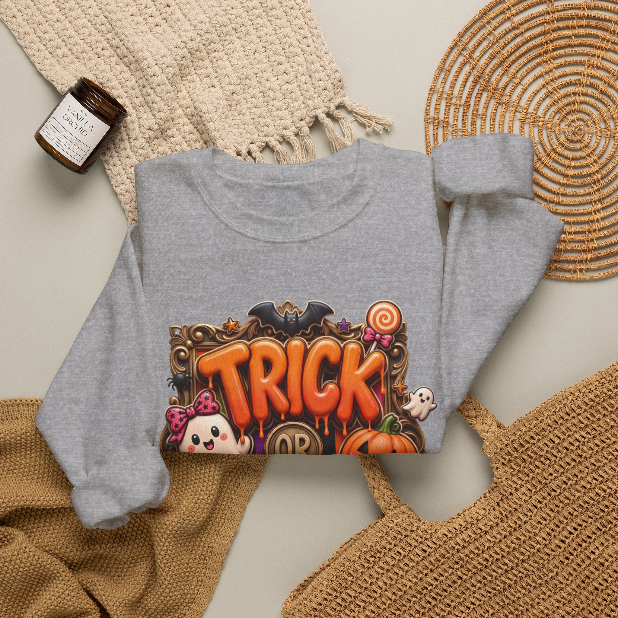Sport Grey crewneck sweatshirt styled flat with a candle — puffy orange trick or treat lettering