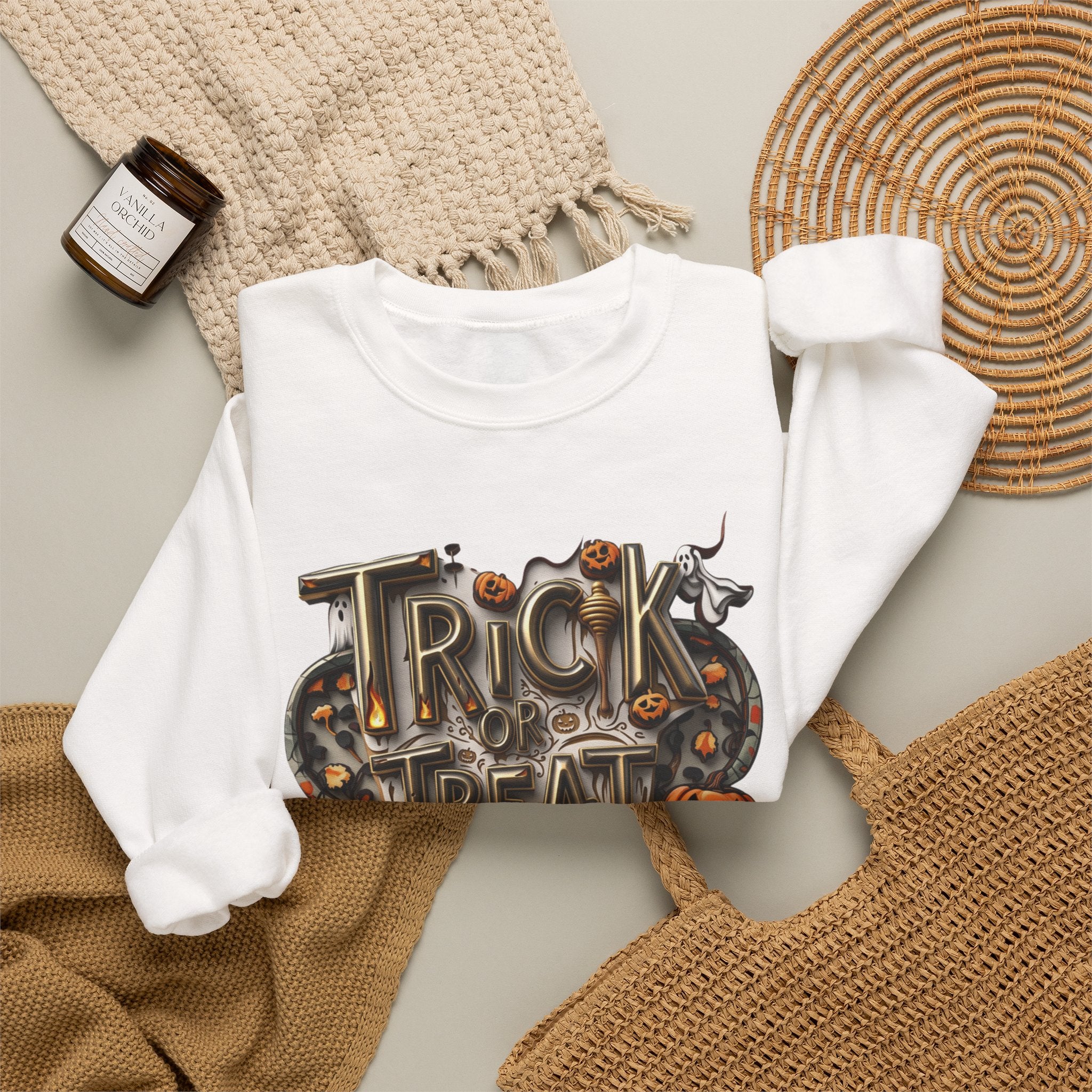 White crewneck sweatshirt styled flat with a candle — carved Trick or Treat Yourself lettering