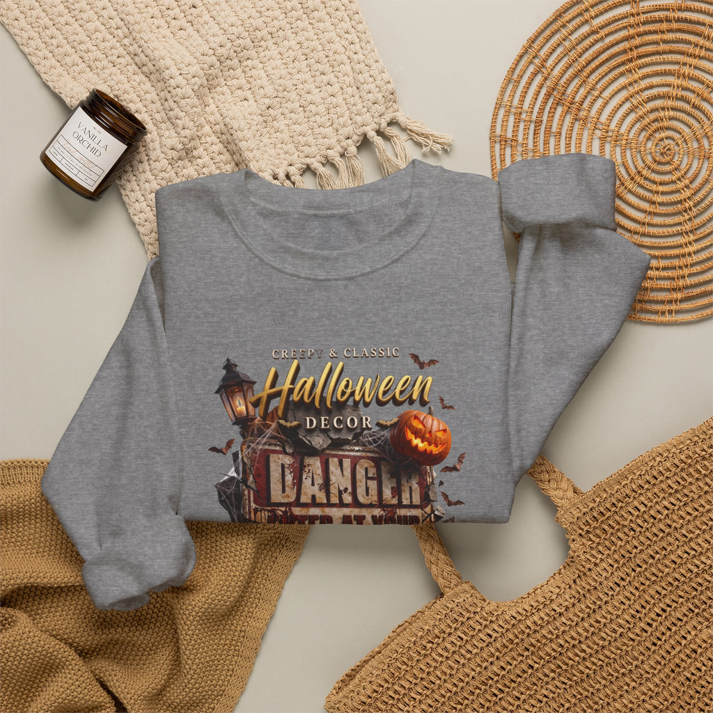 Graphite Heather crewneck sweatshirt styled flat with a candle — aged Danger sign over glowing pumpkins