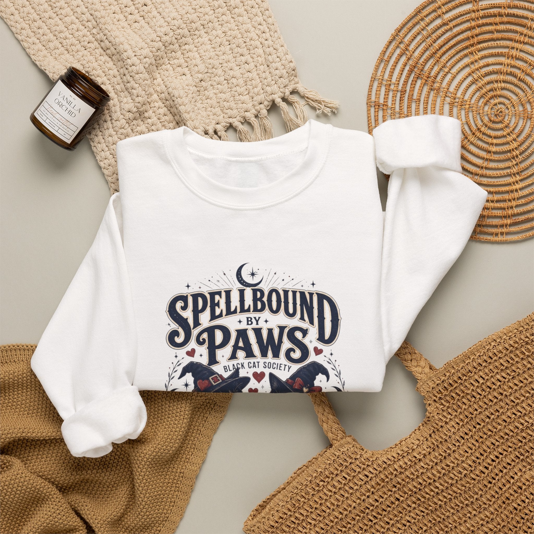 White crewneck sweatshirt styled flat with a candle — two black cats in witch hats