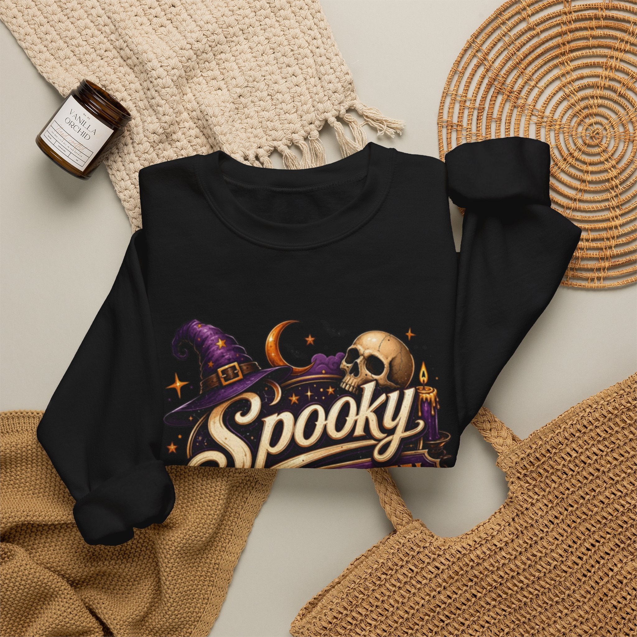 Black crewneck sweatshirt styled flat with a candle — neon Spooky Witch Motel sign