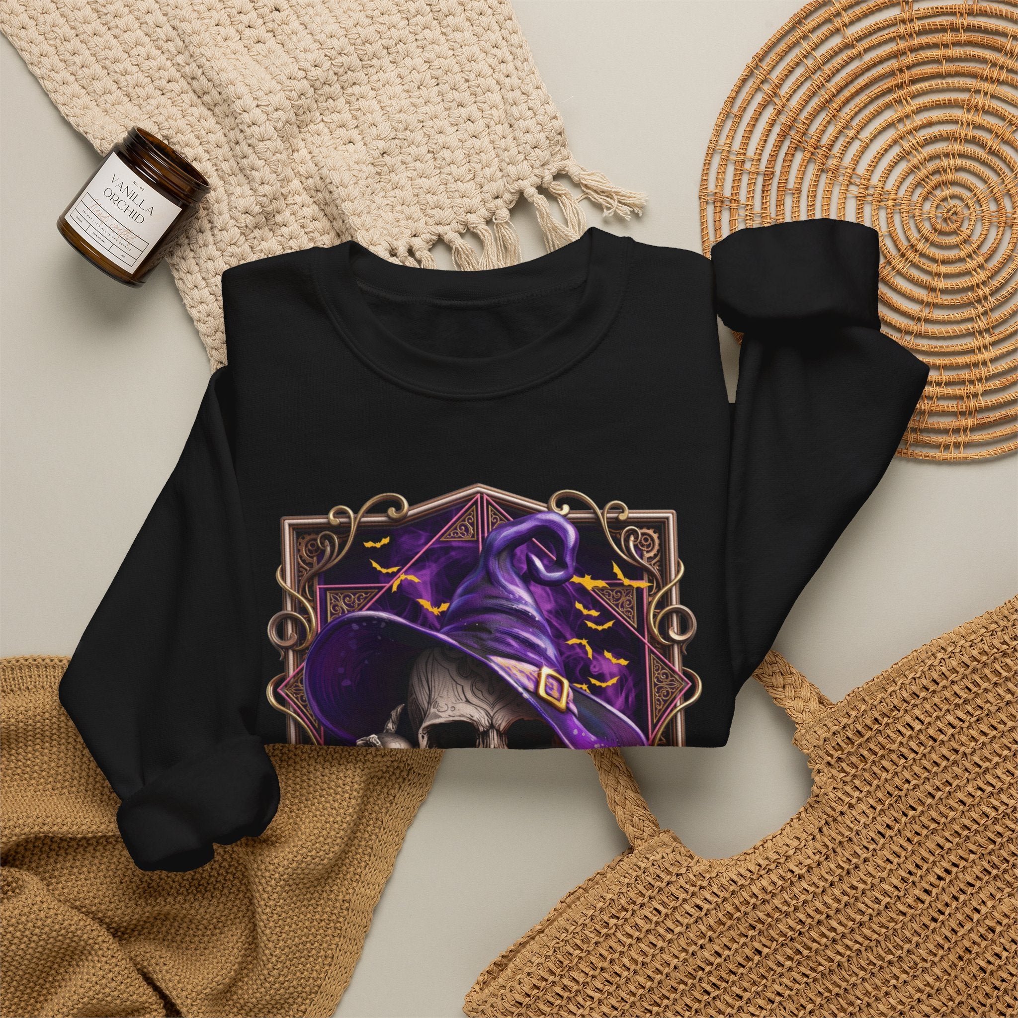 Black crewneck sweatshirt styled flat with a candle — skull in a purple witch hat