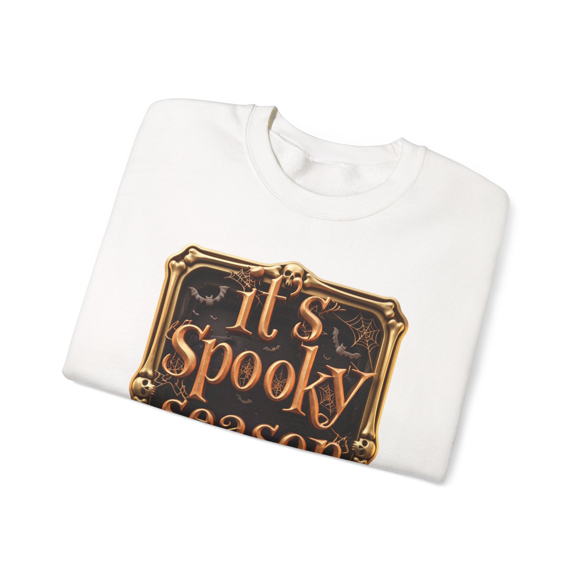 White crewneck sweatshirt folded to show the copper serif lettering reads it's spooky season inside print