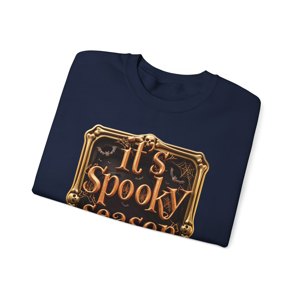 Navy crewneck sweatshirt folded to show the copper serif lettering reads it's spooky season inside print