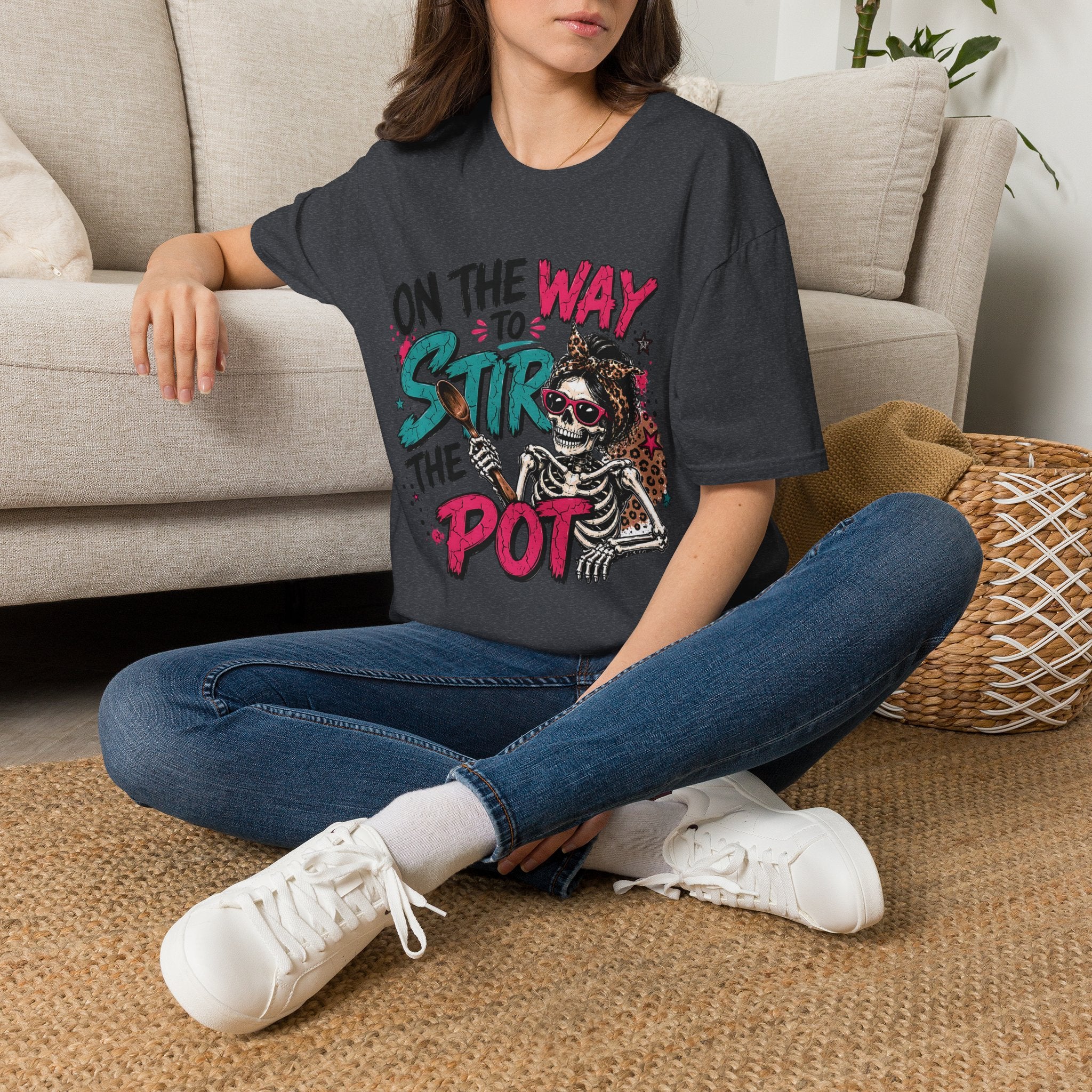 Dark Heather Grey t-shirt laid flat, printed with a skeleton and bold teal and pink lettering reading