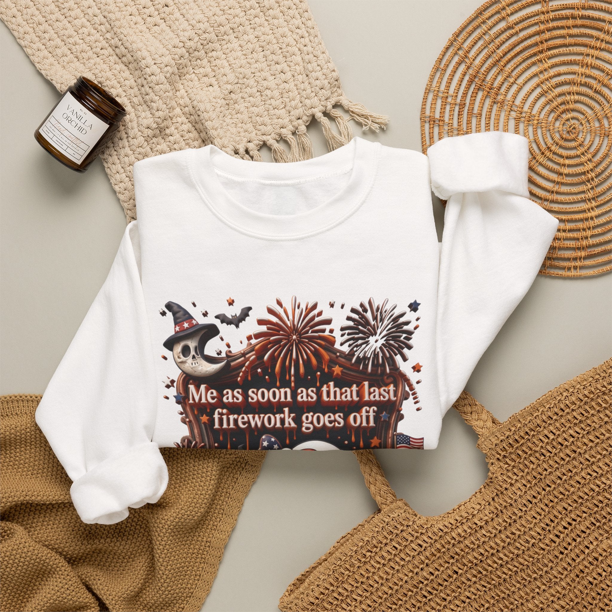 White crewneck sweatshirt styled flat with a candle — wide-eyed ghost clutching a firework