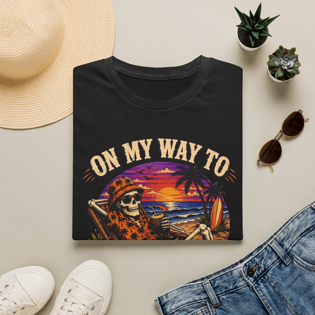Black t-shirt styled flat with a candle — skeleton on a beach at sunset