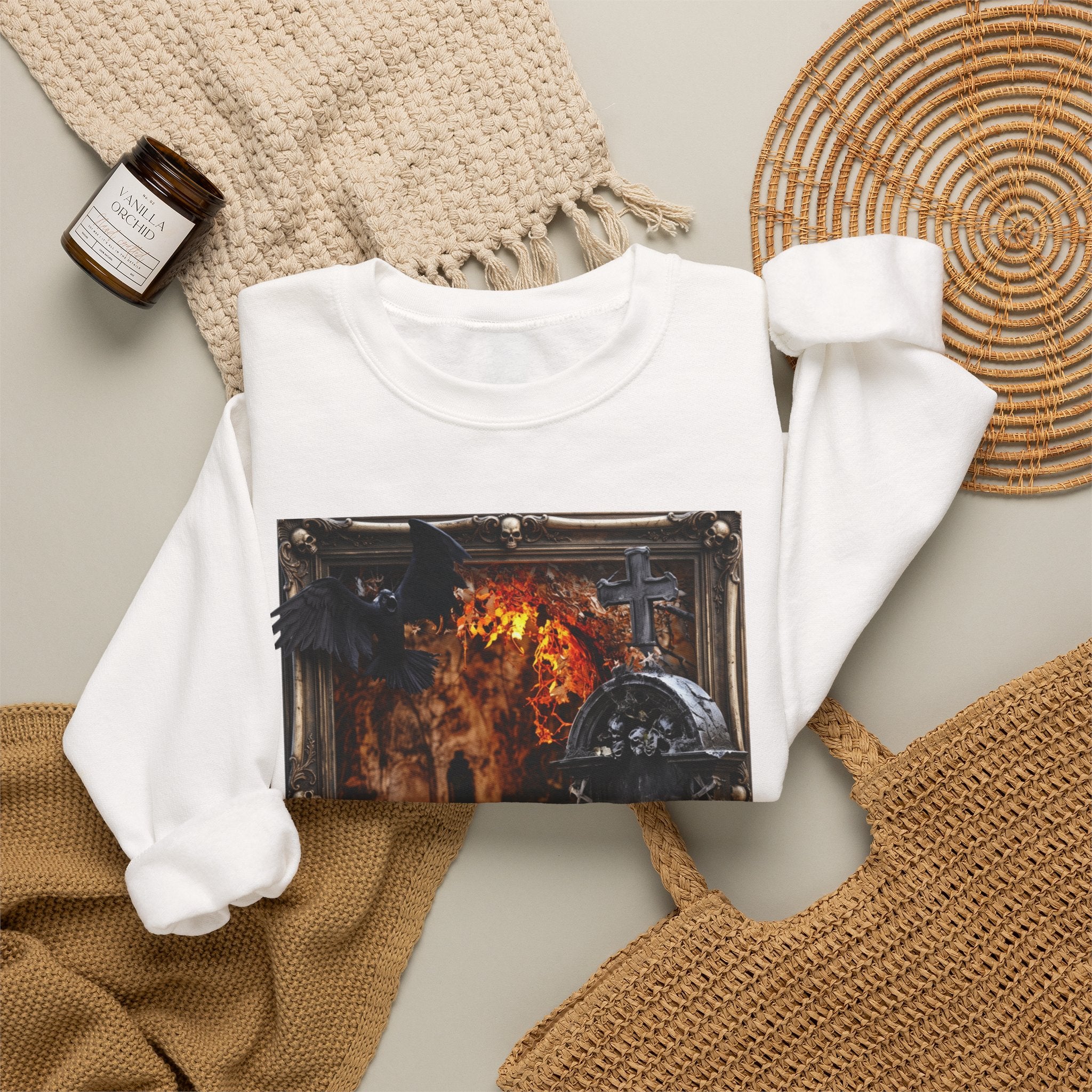 White crewneck sweatshirt styled flat with a candle — framed stone tomb scene