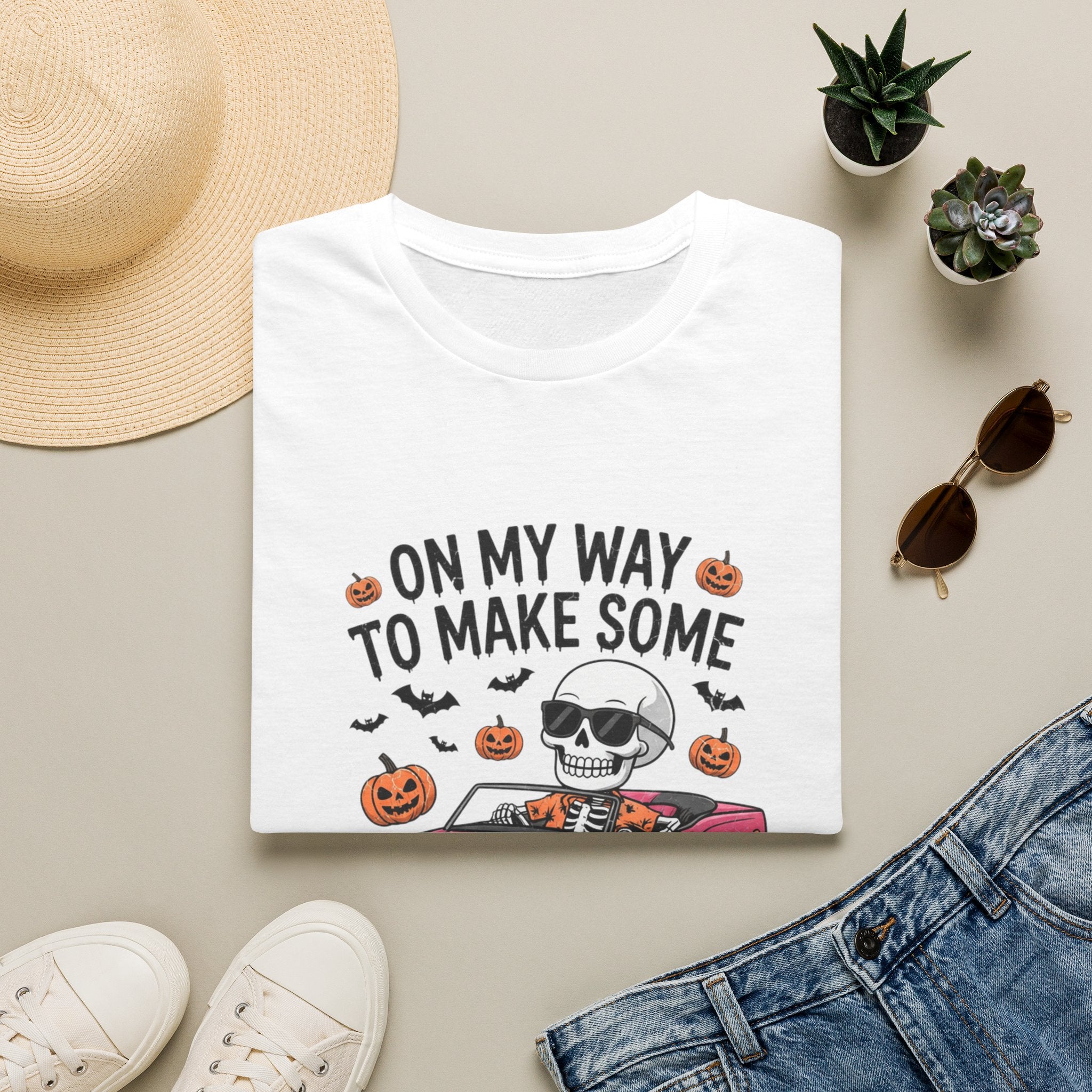 White t-shirt styled flat with a candle — pink convertible car and a skull