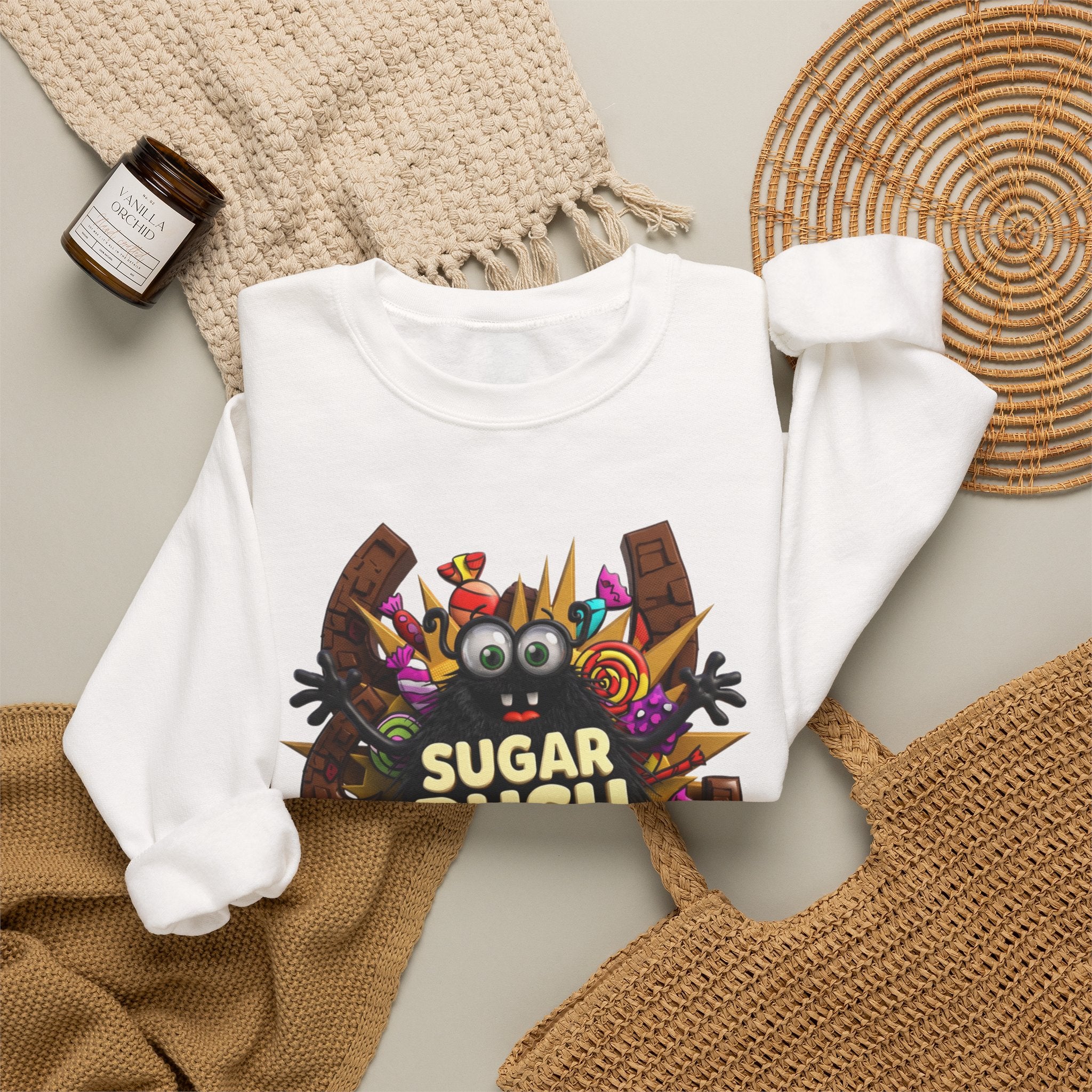 White crewneck sweatshirt styled flat with a candle — fuzzy black monster with googly eyes