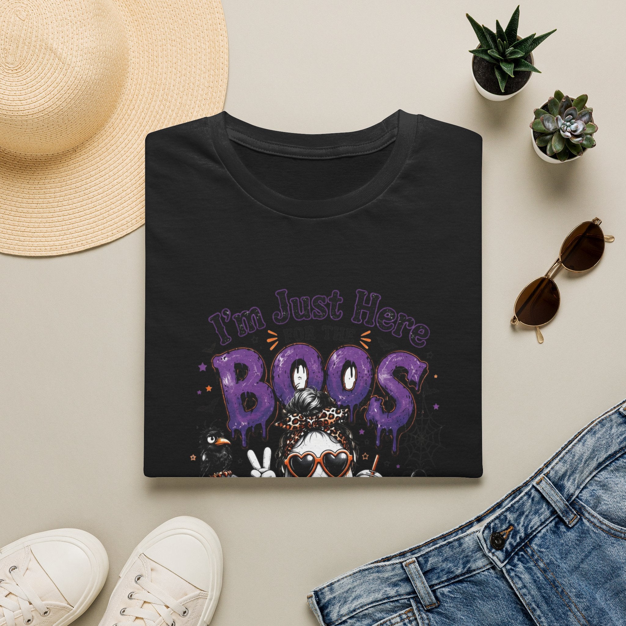 Black t-shirt styled flat with a candle — cartoon ghosts in sunglasses over pumpkins