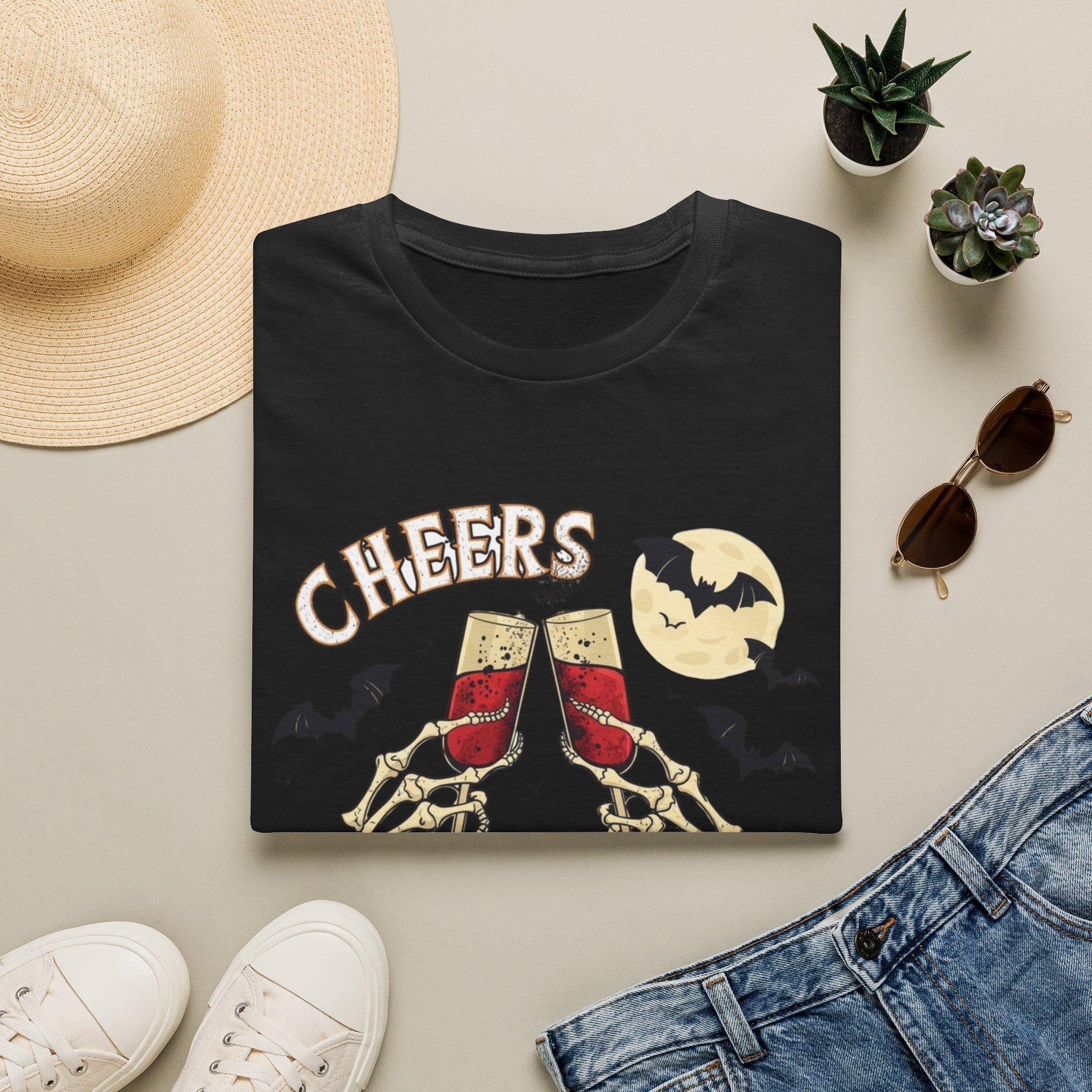 Black t-shirt styled flat with a candle — skeleton hands toasting champagne