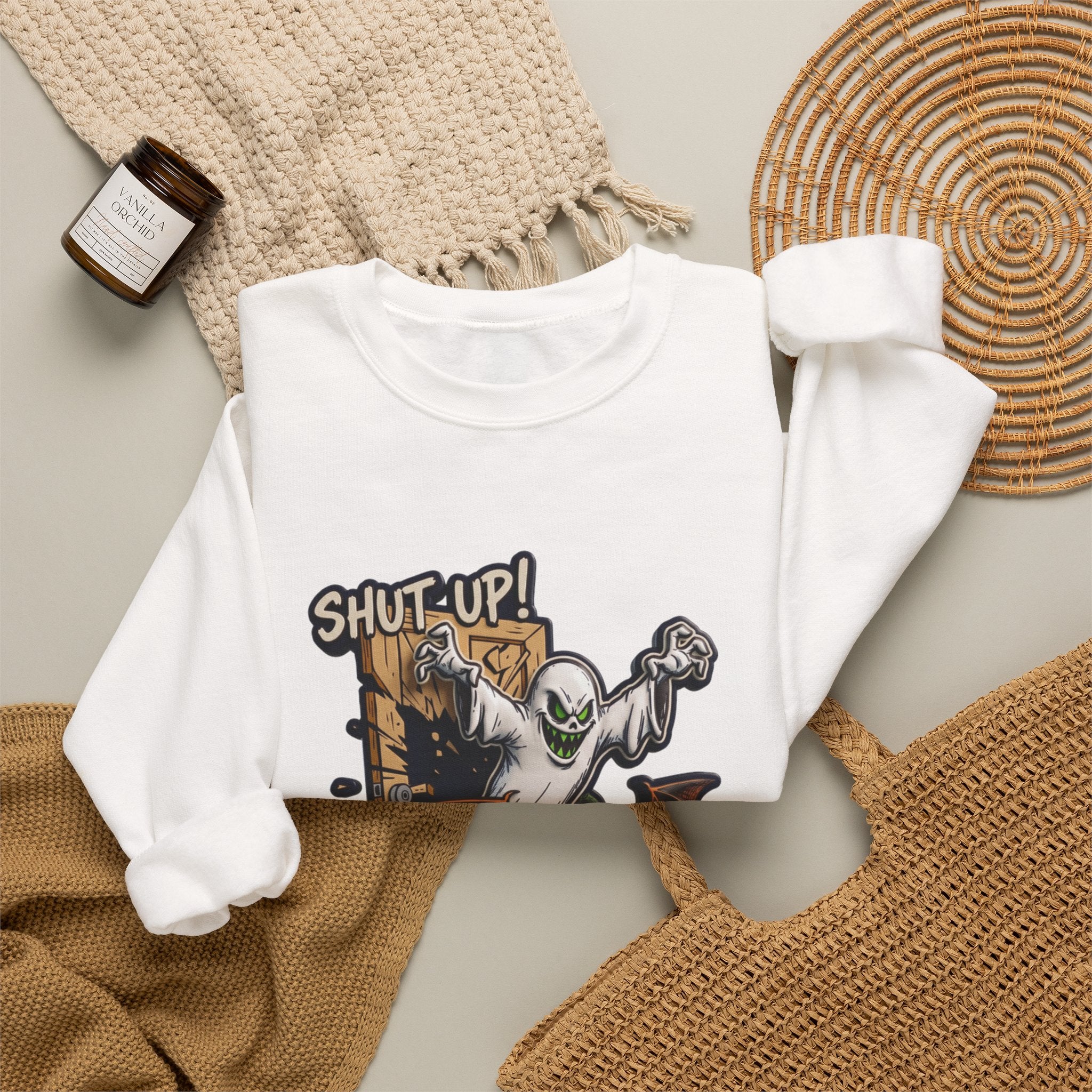 White crewneck sweatshirt styled flat with a candle — green-eyed ghost with bat wings