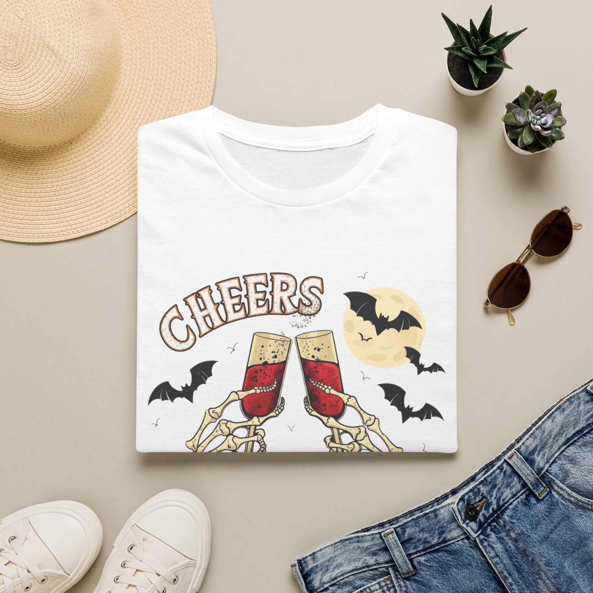 White t-shirt styled flat with a candle — skeleton hands toasting champagne