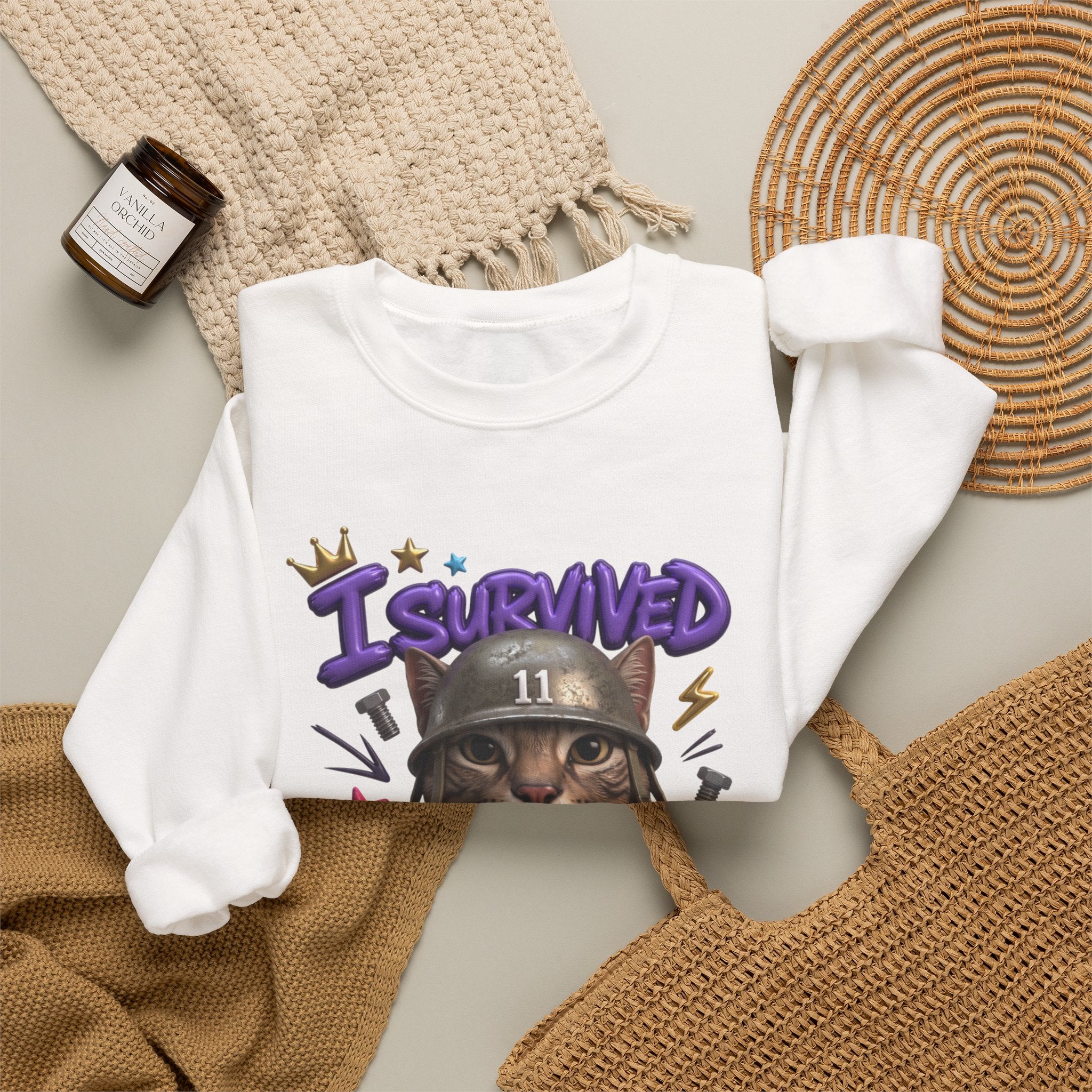 White crewneck sweatshirt styled flat with a candle — flat-eyed cat in a steel helmet