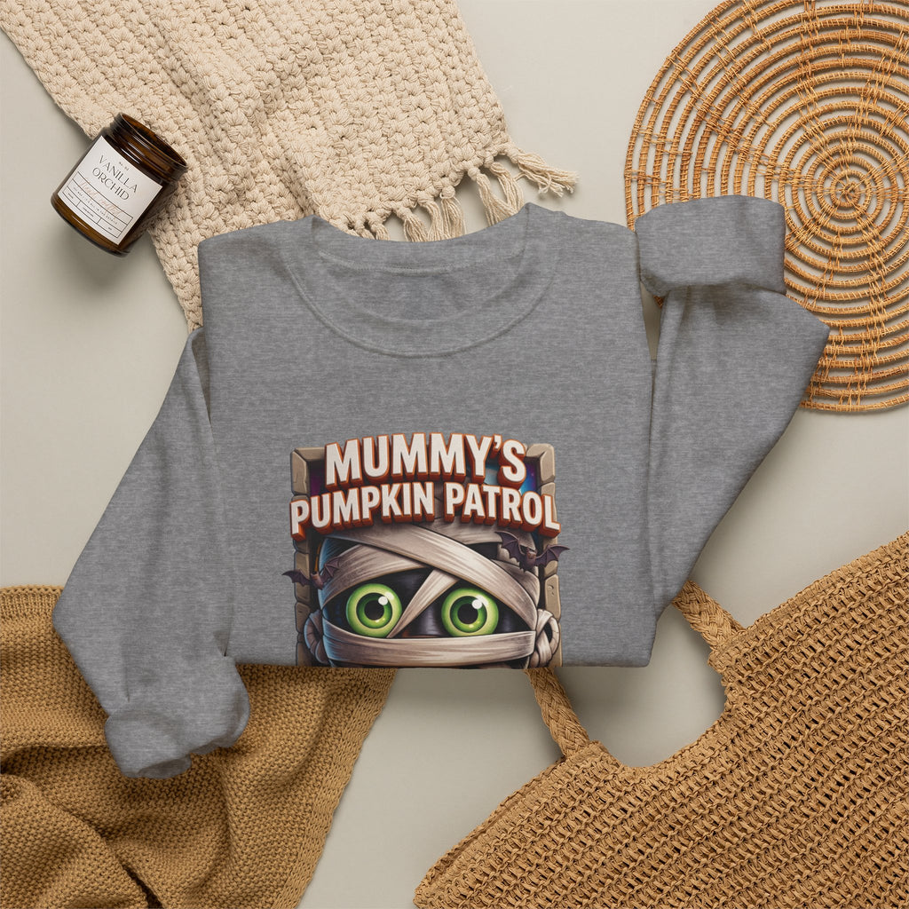 Graphite Heather crewneck sweatshirt styled flat with a candle — cartoon mummy hugging a carved pumpkin