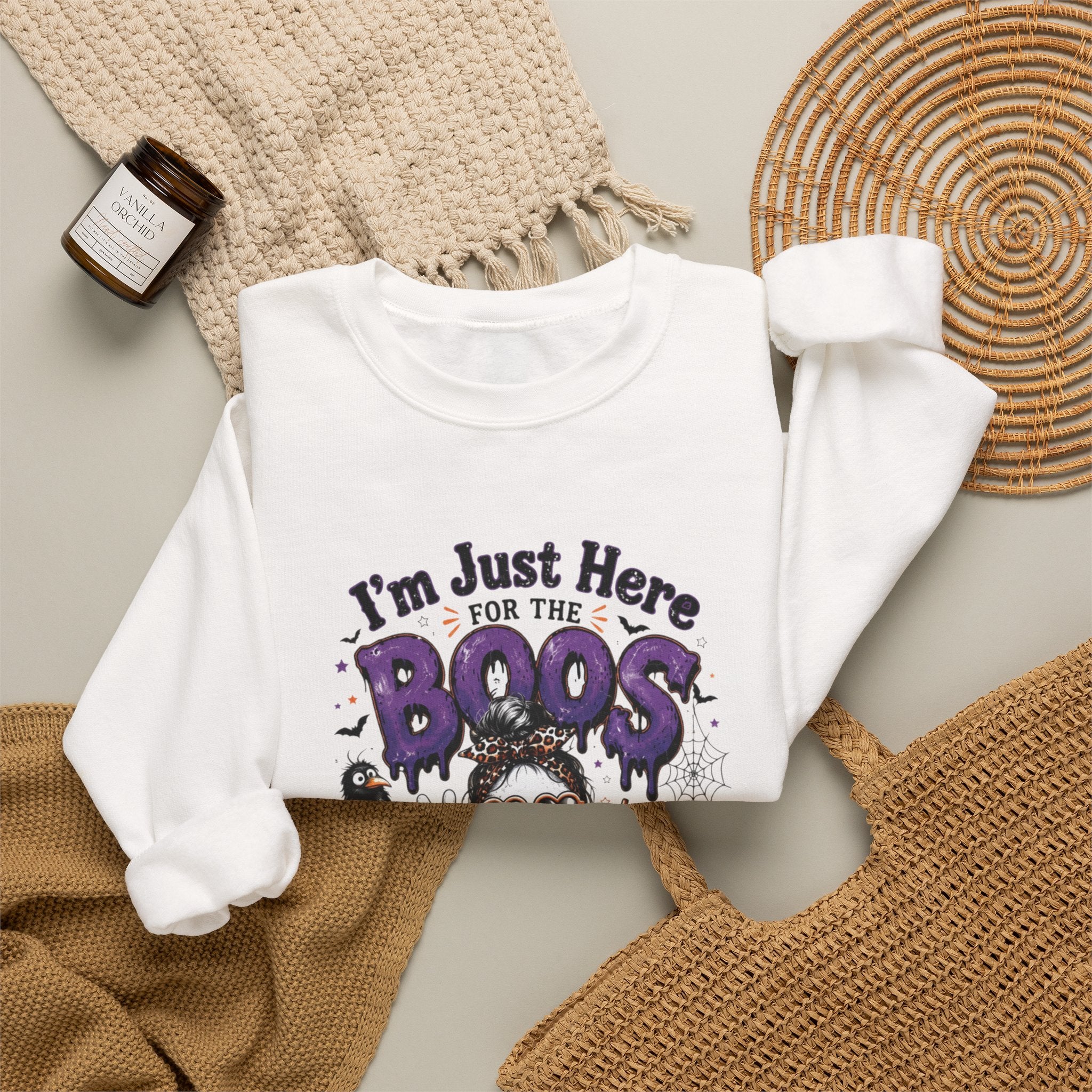 White crewneck sweatshirt styled flat with a candle — three cartoon ghosts in sunglasses